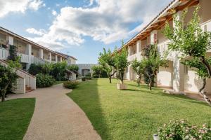 a courtyard of a building with trees and grass at Club Esse Cala Bitta in Baja Sardinia