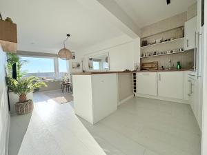 a kitchen with white cabinets and a large window at BEACH apartment met directe toegang tot het STRAND ! in Knokke-Heist