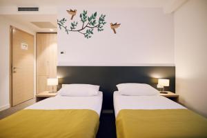 two beds in a room with yellow and white at Hotel Park Superior 3* in Čakovec