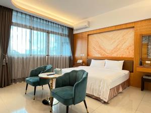 a hotel room with a bed and two chairs at Wind Sea Hill Inn in Hengchun South Gate