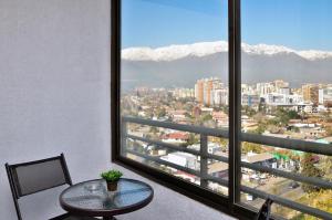 a table and chair in a room with a large window at Norus Las Condes in Santiago