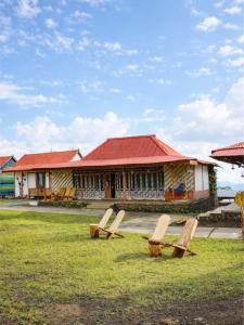 a building with a red roof and benches in the grass at Maza Lodge & Spa in Kejajar