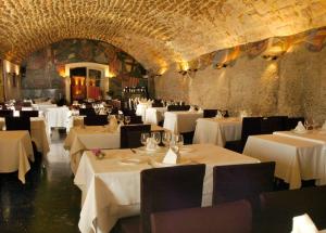 um restaurante com mesas e cadeiras brancas num quarto em Hotel Abat Cisneros Montserrat em Montserrat