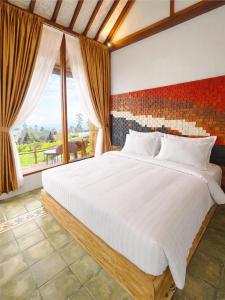 a bedroom with a large white bed and a window at Maza Lodge & Spa in Kejajar