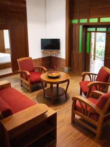 a living room with a table and chairs and a tv at Maza Lodge & Spa in Kejajar