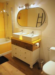 a bathroom with two sinks and a mirror and a toilet at Chez Philomène in Aubusson +20 photos