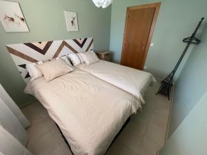 a bed with white sheets and pillows in a bedroom at Apartamento Senda in Comillas