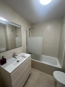 a bathroom with a sink and a tub and a toilet at Apartamento Senda in Comillas +11 photos