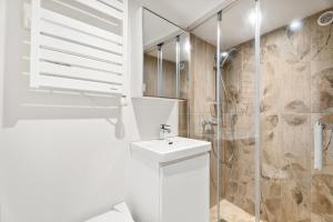 a white bathroom with a sink and a shower at Le Cocon de la Combe - Maisonnette pour 4p in Coursegoules