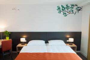 a bedroom with a bed and two tables and two lamps at Hotel Park Superior 3* in Čakovec