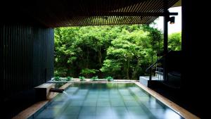 a swimming pool in a house with trees in the background at Aizu-Wakamatsu "Yukkura Inn" self-service INN in Aizuwakamatsu