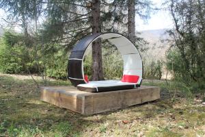 an arch shaped bed in a forest with two red chairs at Chalet toit vegétalisé in Champfromier