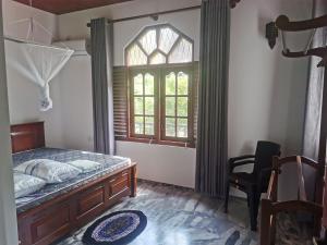 a bedroom with a bed and a window and a chair at Villa Rina in Kottagoda