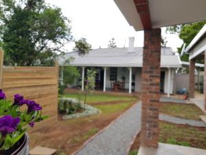 a house with a fence and flowers in the yard at Coach House Bed and Breakfast in Greytown
