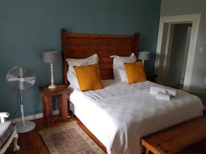 a bedroom with a bed with orange pillows and a fan at Coach House Bed and Breakfast in Greytown