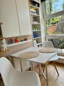 two white tables and chairs in a room with a window at Studio face au château de Thy in Thy-le-Château