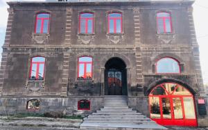 a building with red windows and stairs in front at Miassine Boutique Hotel in Gyumri