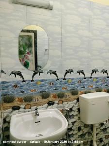 a bathroom with a sink and birds on the wall at isha homestay in Varkala