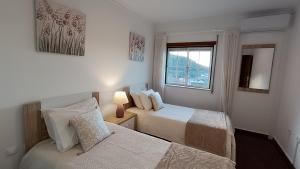 a bedroom with two beds and a window at Lousã's Brown & White in Lousã