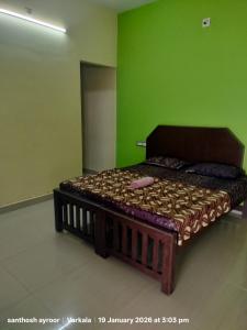 a bed in a room with a green wall at isha homestay in Varkala