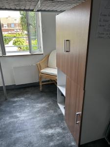 a room with a cabinet and a chair and a window at Petite chambre in Halluin