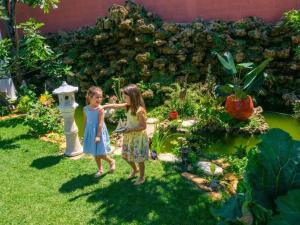 two little girls are standing in a garden at La Villa des Roses Gîte Chambres d'hôtes Piscine chauffée in Luçon