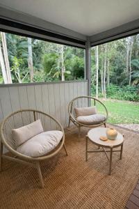 two chairs and a table on a screened in porch at Private Rainforest Guesthouse in Doonan in Doonan +1 photo