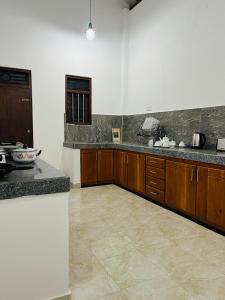 a kitchen with wooden cabinets and marble counter tops at Manthraa Holiday Apartment in Ratgama Hegoda