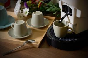 a table with cups and saucers and a coffee maker at Merlino Urban Suites in Messina +8 photos