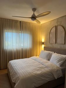 a bedroom with a white bed with a ceiling fan at Shilo Boutiqe Suites in Mishmār Hāyardin +36 photos