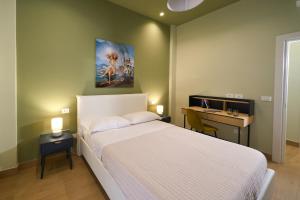 a bedroom with a white bed with a desk and a painting at Merlino Urban Suites in Messina