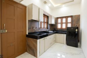 a kitchen with white cabinets and black counter tops at Reunion Ocean Hridayam - Beach House in Udupi