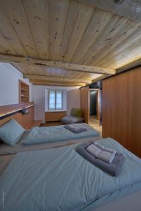 two beds in a bedroom with a wooden ceiling at BnB Ai Cav Calanca in Arvigo