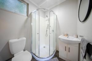 a bathroom with a shower and a toilet and a sink at Stoneybrook Cabins in Waimauku +15 photos