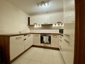 a white kitchen with white cabinets and a sink at Wokingham Stylish Two Bedroom Apartment in Wokingham +1 photo