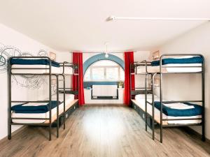 a room with three bunk beds and a window at Ostello Bello Genova in Genoa