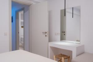 a white bathroom with a sink and a mirror at White Cliff Villas Paros in Ambelas