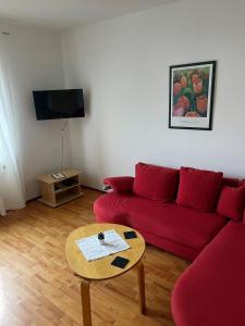 a living room with a red couch and a table at Zum Seeweiher in Dreifelden