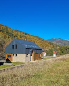 a house with a black roof on top of a field at Chata Zingoty in Mýto pod Ďumbierom