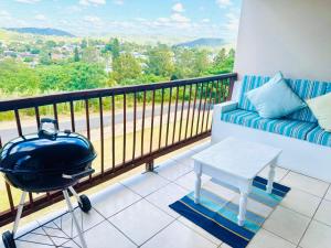 a balcony with a couch and a table and a grill at The Cherry Apartment Nahoon Valley in East London