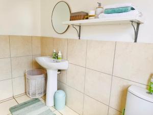 a bathroom with a sink and a mirror at The Cherry Apartment Nahoon Valley in East London +8 photos