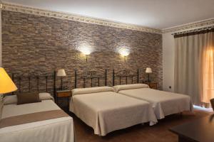 a bedroom with two beds and a brick wall at Hotel Trajano in Zalamea de la Serena
