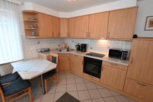 a kitchen with wooden cabinets and a table and a microwave at Bernstein Mare-Supreme Wohnung 4 in Büsum