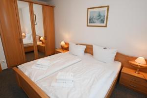 a bedroom with a bed with white sheets and towels at Bernstein Mare-Supreme Wohnung 4 in Büsum