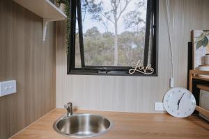 a sink in a bathroom with a window and a clock at Pigeon Pair Tiny Houses by Tiny Away in Tallarook