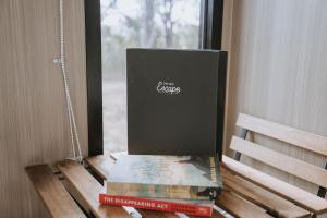 a stack of books sitting on a table next to a window at Pigeon Pair Tiny Houses by Tiny Away in Tallarook