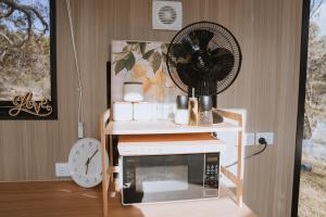 a microwave on a table with a fan and a clock at Pigeon Pair Tiny Houses by Tiny Away in Tallarook