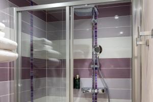 a shower in a bathroom with purple and white tiles at Hôtel du Plat d'Etain in Paris +107 photos
