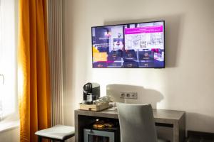 a room with a table and a tv on the wall at Hôtel du Plat d'Etain in Paris