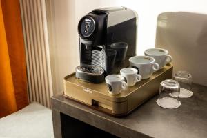 a coffee maker and coffee cups on a table at Hôtel du Plat d'Etain in Paris
